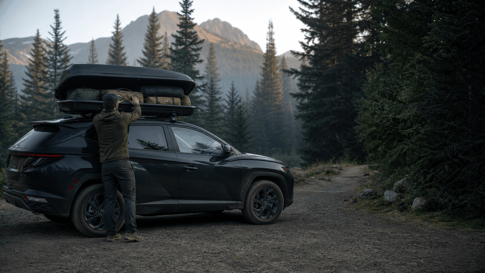 Traveler packing a generic rooftop cargo box at a forest trailhead